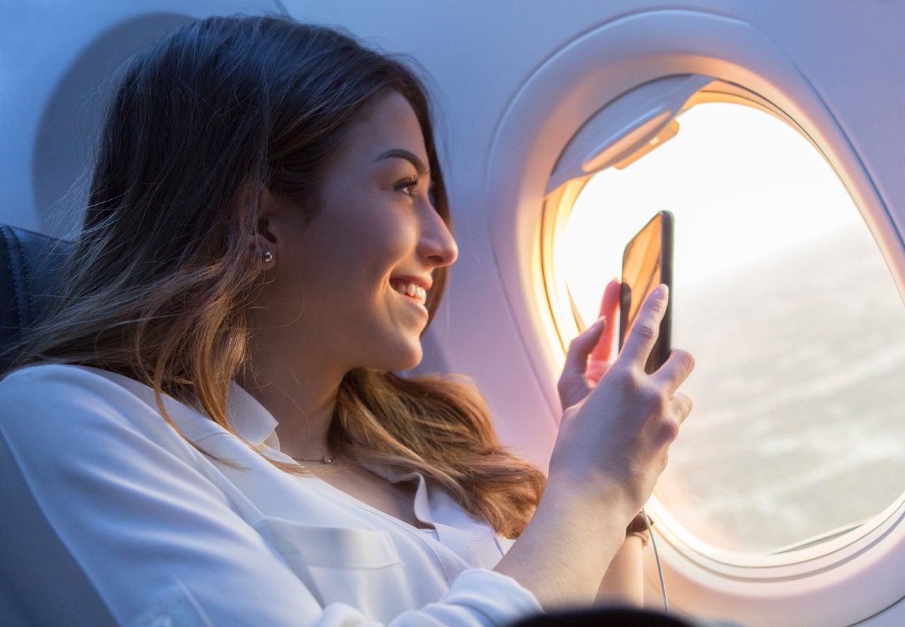 A happy Unitd Airlines customer holds their device out of the plane window to take a photo of the sunrise.