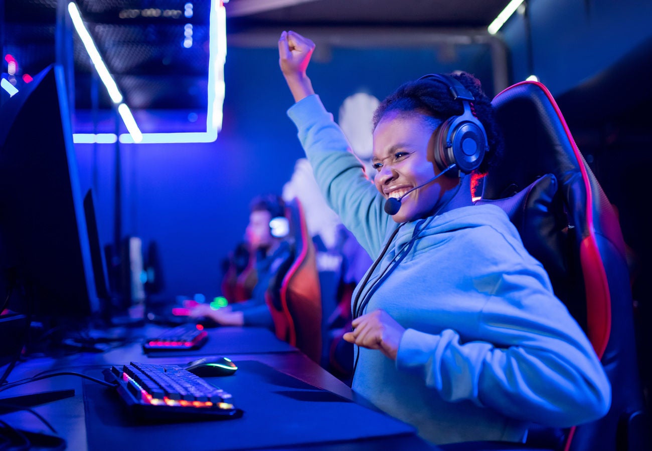 story riot games header 1300x900 A female gamer celebrates a victory.